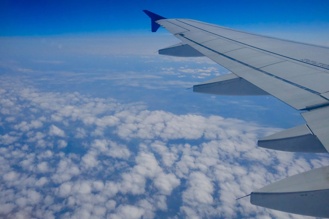Gruppenbuchung bei Billigfliegern – Flugzeugflügel über einer Wolkendecke